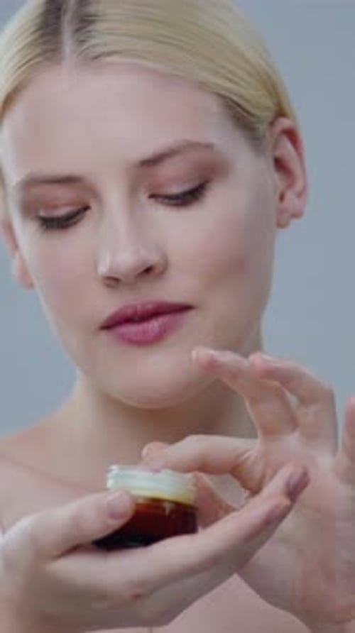 Blonde Woman Applies Cream to Her Face