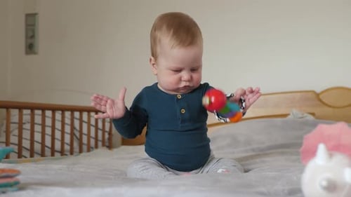 Baby Plays with Colorful Toy on Bed