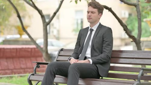 Stressed Man Rubbing Temples on Park Bench