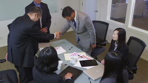 Diverse group of professionals at conference table handshake