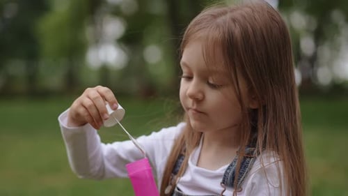 A Joyful Child is Happily Playing with Bubble Solution in a Vibrant Park Setting