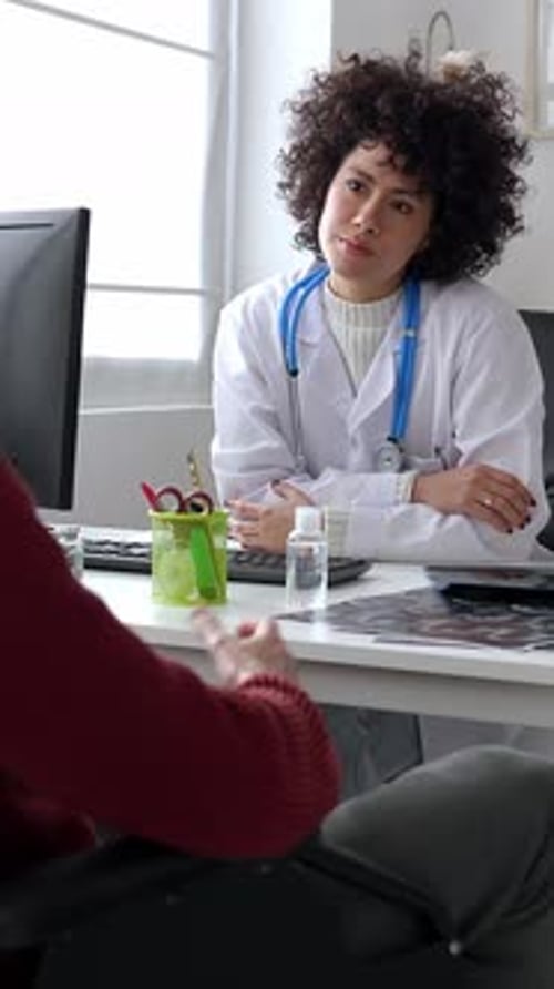 Doctor and Patient in Wheelchair Talking in a Medical Consultation in a Clinic