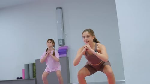 Woman and Child Doing Squats and Planks Together
