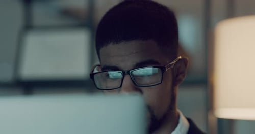 4k video footage of young businessman using a computer during a late night in a modern office