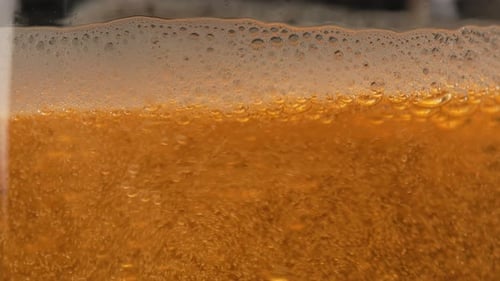 Cerveja light é colocada em um close-up de vidro. Bolhas de cerveja e espuma espirram na caneca. Refrescante