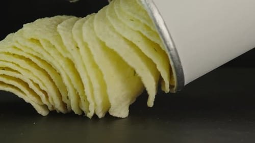 Potato chips pouring from tube bag macro. Snack for drinks close up. Golden fried potatoes. Crispy