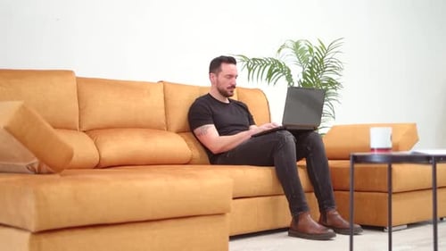 Man Working on Laptop While Sitting on Couch