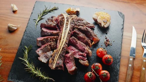 Mittelseltenes T-Bone-Steak in Scheiben mit Kräutern und Knoblauch.