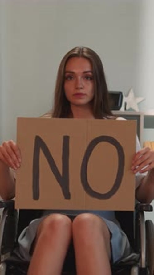 Woman in Wheelchair Holding "NO" Sign
