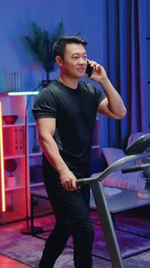 Man on Treadmill Talking on Phone Indoors