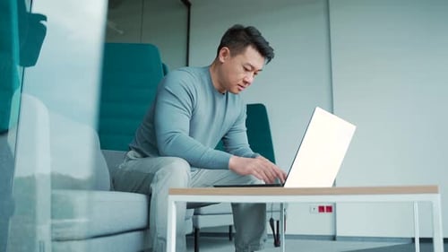 Asian male freelancer working on laptop in modern office coworking center Man student or teacher