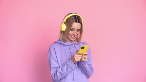 Smiling Woman Using Phone With Headphones On
