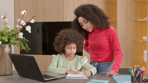 Caring African American Mother Helping Cute School Age Daughter with Homework