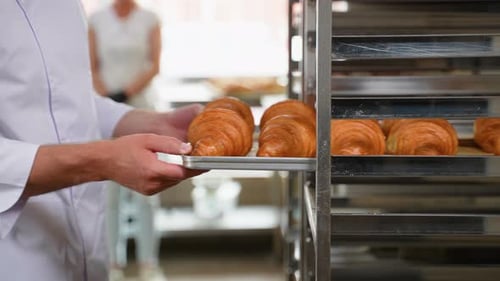 Baker Taking Fresh Croissants from Oven