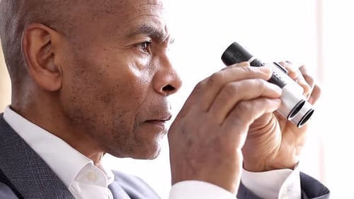 Man Looking Through Binoculars Indoors During the Day