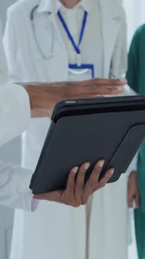 Doctors Consulting on Tablet Device in Hospital