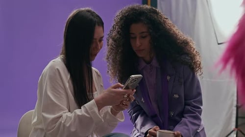 Photographer Assistant Sharing Pictures on Phone with Model in Photo Studio