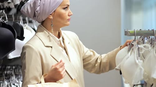 Woman Shopping for Bras in Clothing Store