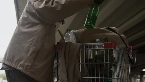 Homeless Man with Shopping Cart Puts Bottles Inside