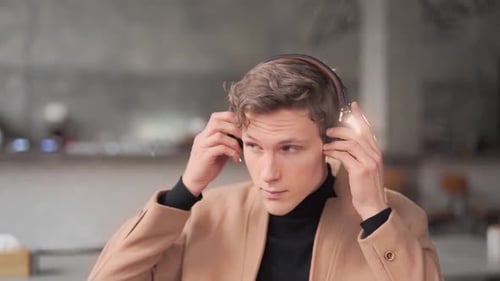 Young Adult Putting On Headphones Indoors
