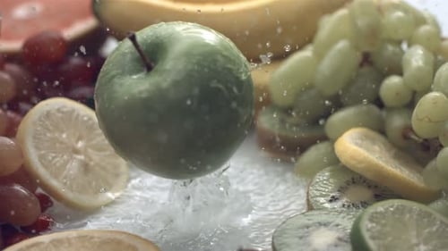 Fresh Apple Falls Among Colorful Fruit and Water