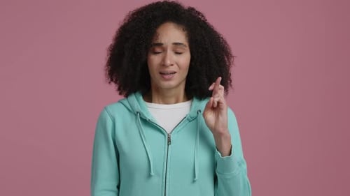 Woman With Curly Hair Crossing Fingers on Pink