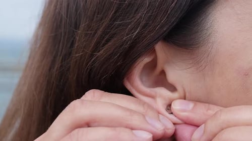 Woman Removing Flower Earring by the Water