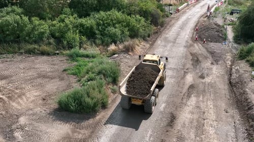 Yellow Dump Truck Driving on Rural Dirt Road