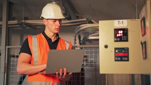Engineer Confidently Operates Laptop Ensuring Safety in Industrial Facility