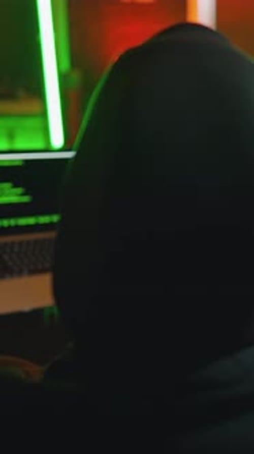 Back View of Hacker or Anonymous Internet User in Black Hoodie Working with Powerful Computer in