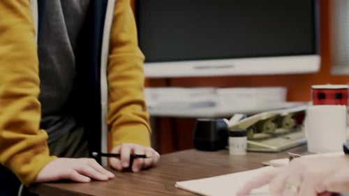 Teacher Helping Junior High Student with Homework at Desk in Classroom 1213 Years