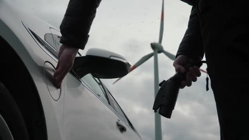 Charging Electric Car with Wind Turbine in Background