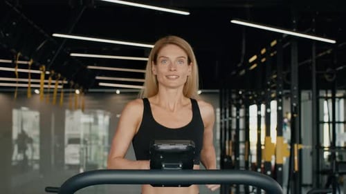 Smiling Woman Jogging on Treadmill in Gym