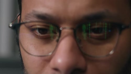 Man in Eyeglasses Reflection of Green Numbers in Glasses Male Programmer in Front of Display Looking