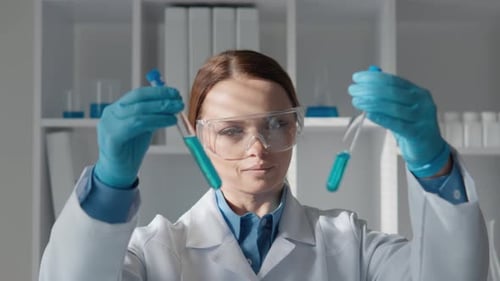 Woman scientist holding test tubes with blue liquid