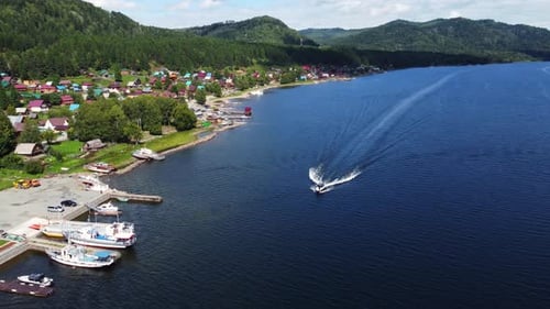 Aerial view of tourist boat moving along mountainous lake water surface on sunny day. Water transpor