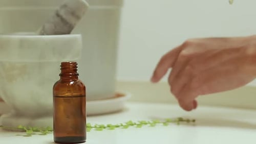 Utiliser une solution provenant d'un flacon en verre brun avec un compte-gouttes pour hydrater les mains avec un mortier et un pilon b