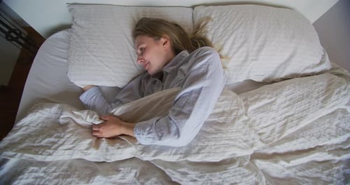 Smiling Woman Stretching in Bed in Morning