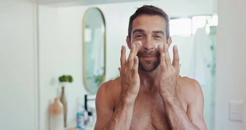 Man Applies Moisturizer to Face in Bathroom