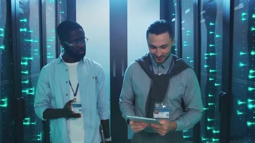 IT Professionals Walk Through Server Room with Tablet