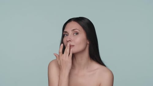 A Woman Touches Her Lips While Moisturizing Them on a Blue Background Close Up A Woman Applies Lip