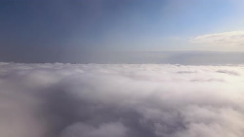 Aerial View From Airplane Window at High Altitude of Earth Covered with White Puffy Cumulus Clouds