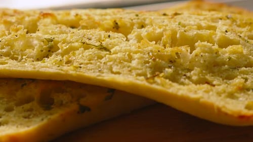 Ralentissement : déplacement sur du pain ciabatta artisanal à l'ail et aux herbes fraîchement cuit sur une planche de bois
