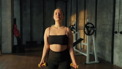 Woman Does Bicep Curls with Weights in Gym