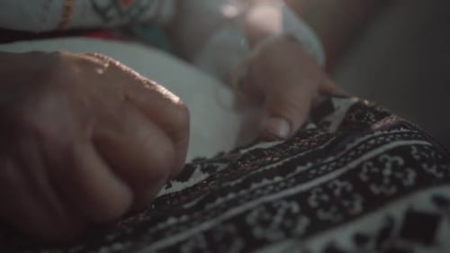 Hands Embroidering Intricate Fabric with Needle and Thread