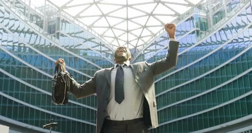 Businessman Celebrates Success Near Modern Skyscraper