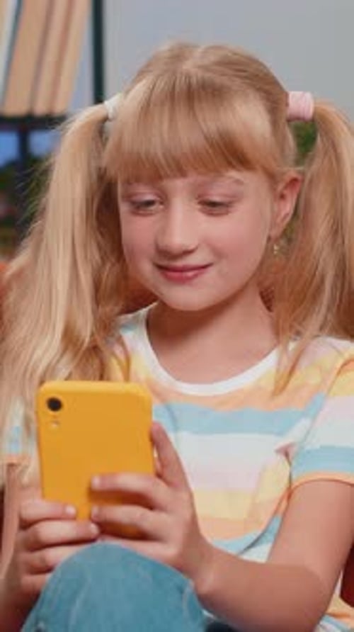 Smiling girl using smartphone indoors