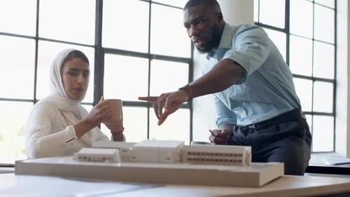 Discussing architectural model, business colleagues collaborating in modern office