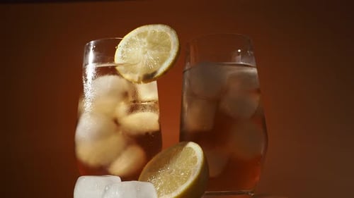 Rotating Iced Tea in a Glass with Ice Cubes on an Orange Background