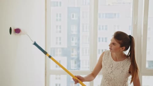 Woman Painting Wall in Apartment with Roller